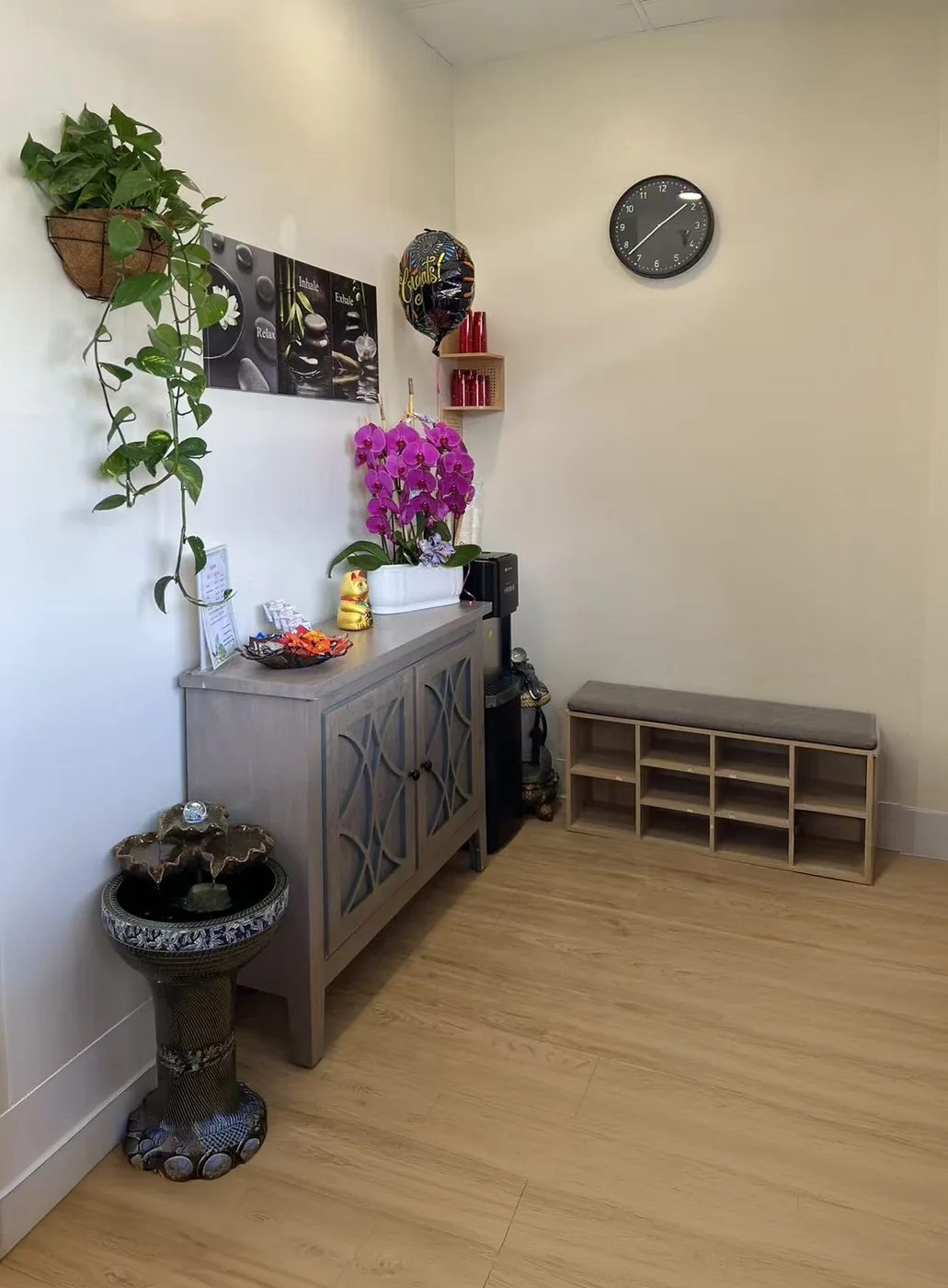 Wide view of the front lobby showing shoe storage bench, cabinet, water fountain and orchids