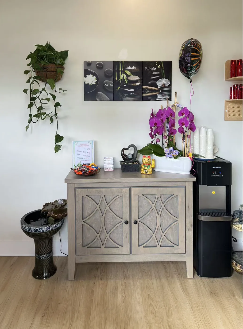 Lobby corner with Relax Inhale Exhale wall art, water dispenser, fresh orchids and small fountain
