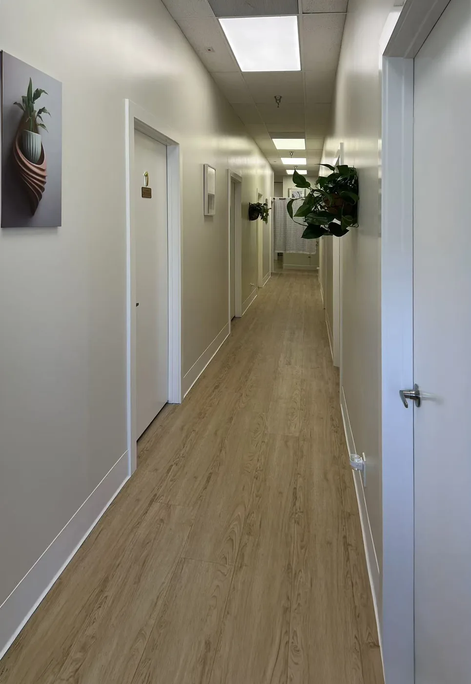 Hallway with light wood flooring leading to the private treatment rooms